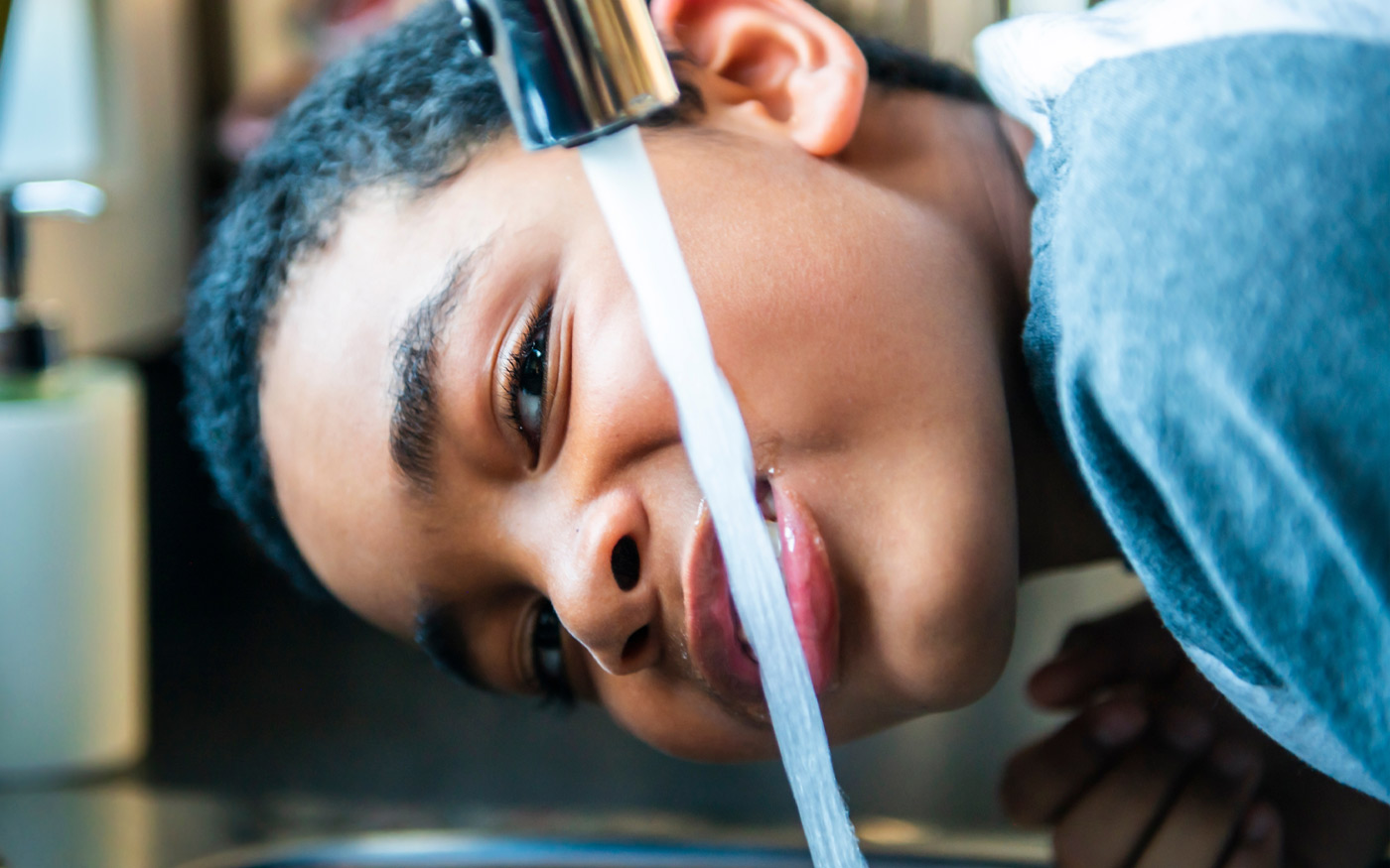 Enfant qui boit de l'eau au robinet, thème "la confiance en l'eau du robinet”